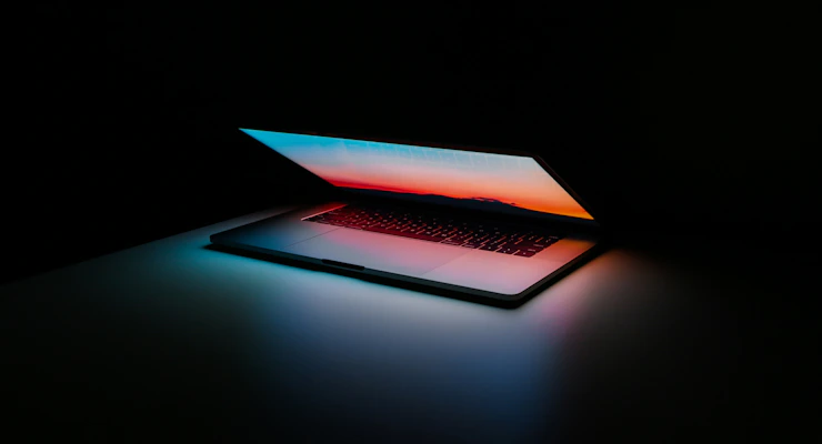 Laptop em secretária com ambiente de desenvolvimento — ecrã com código
